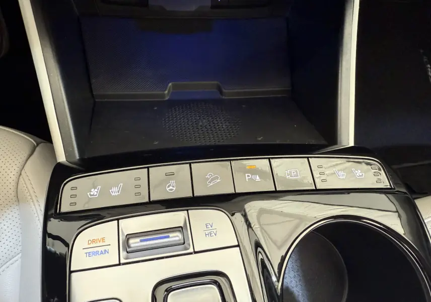 Gros plan sur la console centrale noire brillante du Hyundai Tucson 2022 avec commandes de sièges chauffants et modes de conduite.