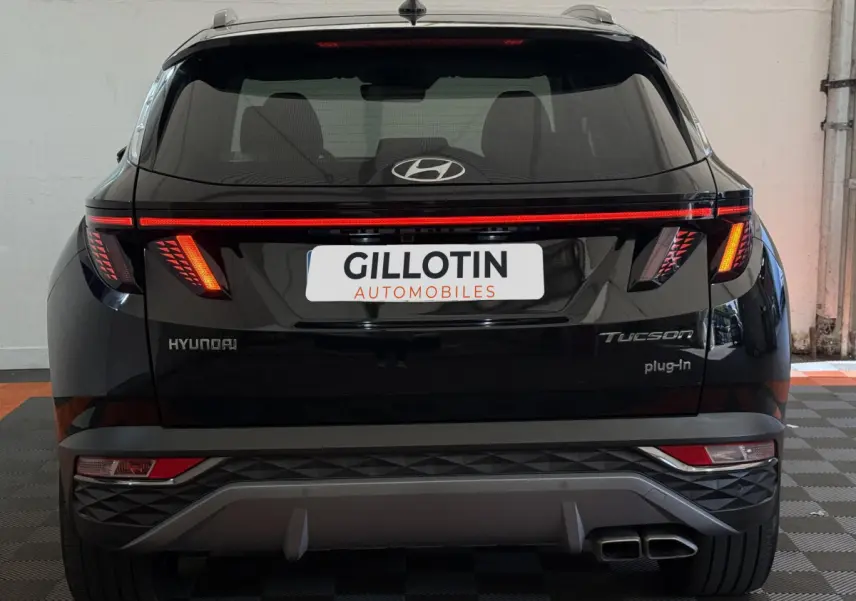 Vue arrière d'un Hyundai Tucson noir avec feux LED allumés et double sortie d'échappement visible.