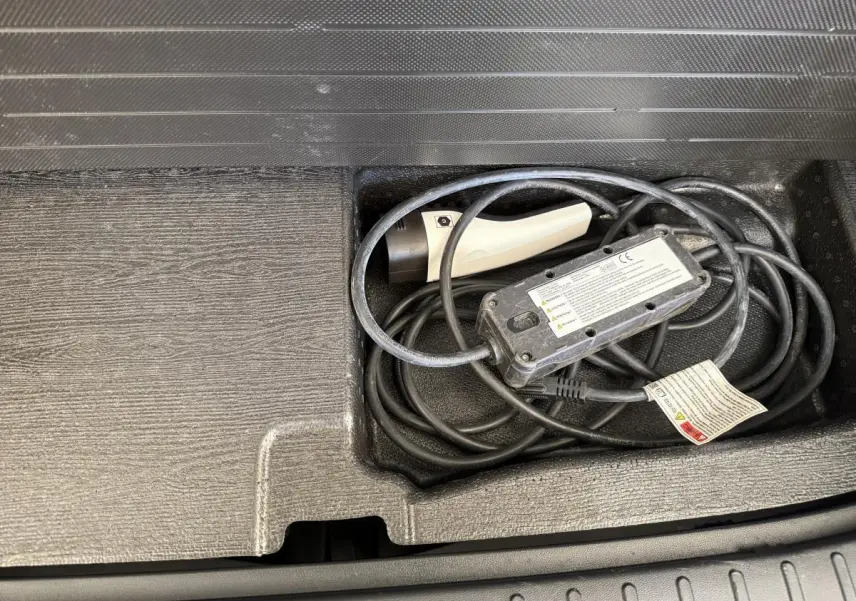 Gros plan sur le câble de recharge rangé dans le coffre du Hyundai Tucson noir hybride rechargeable 2022.