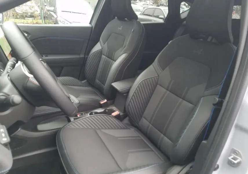Intérieur du Renault Captur 2025, vue côté conducteur, sièges sport noirs avec surpiqûres bleues et logo Alpine brodé.