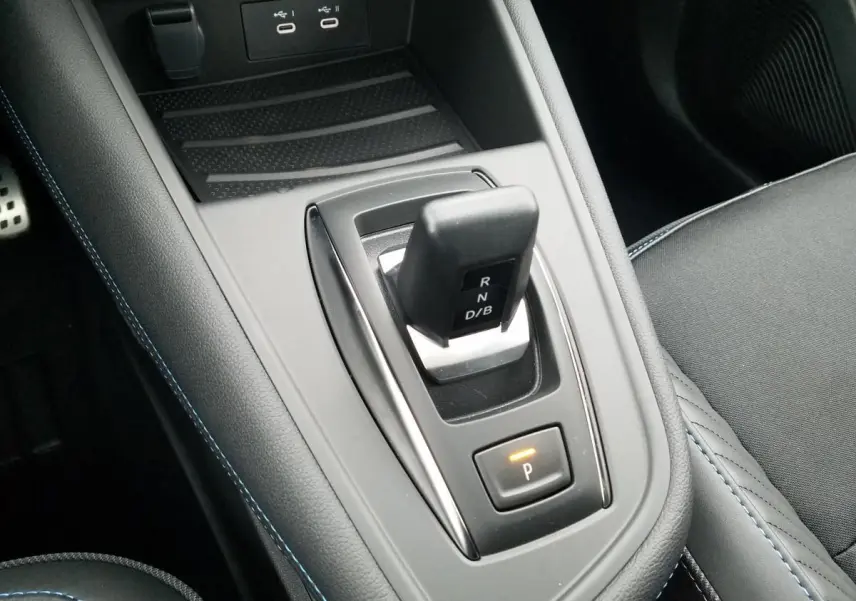 Gros plan sur la console centrale du Renault Captur 2025 avec levier de vitesses automatique et surpiqûres bleues.