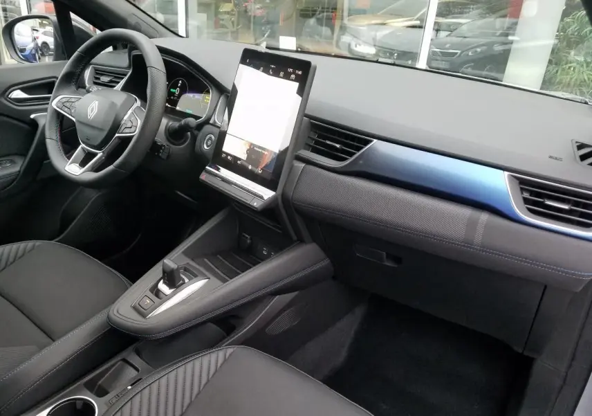 Intérieur avant droit du Renault Captur 2025 avec tableau de bord noir, écran tactile vertical et sellerie noire.