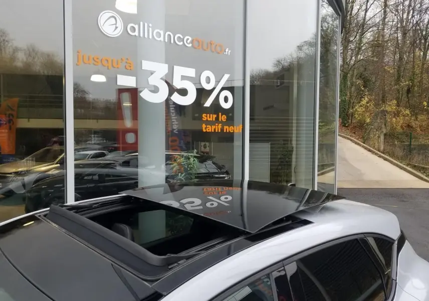 Toit ouvrant électrique ouvert sur le côté gauche d'un Renault Captur gris Rafale avec coques de rétroviseurs noires.