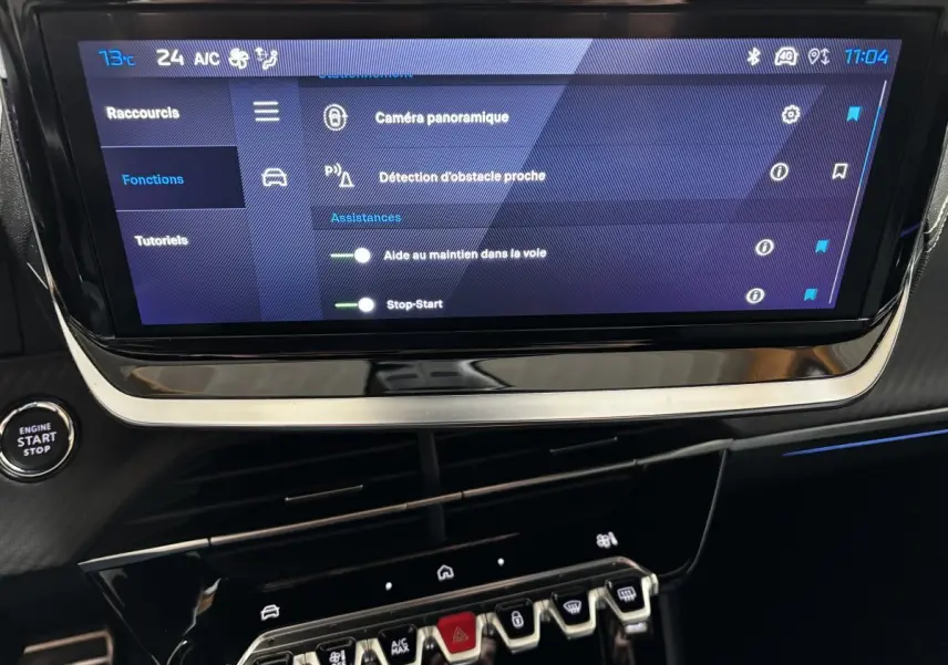 Écran tactile central affichant les aides à la conduite dans l’habitacle d’une Peugeot 208 Hybrid gris clair.
