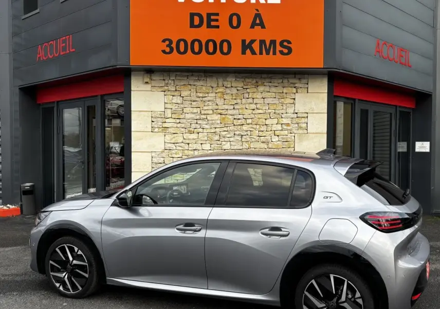 Vue latérale droite d'une Peugeot 208 Hybrid 110 e-DCS6 GT gris clair avec jantes noires et toit panoramique.