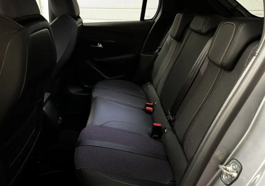 Vue intérieure côté arrière droit de la banquette arrière en tissu et cuir noir avec surpiqûres jaunes du Peugeot 208 Hybrid 110 e-DCS6 GT gris clair.