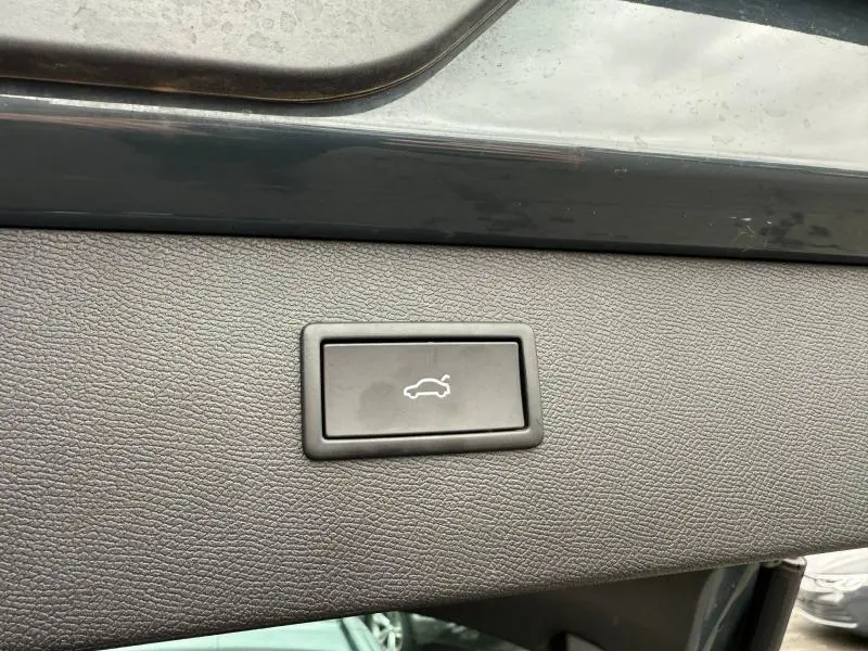 Bouton d'ouverture électrique du coffre sur la garniture intérieure d'une CUPRA Formentor bleu, vue rapprochée.