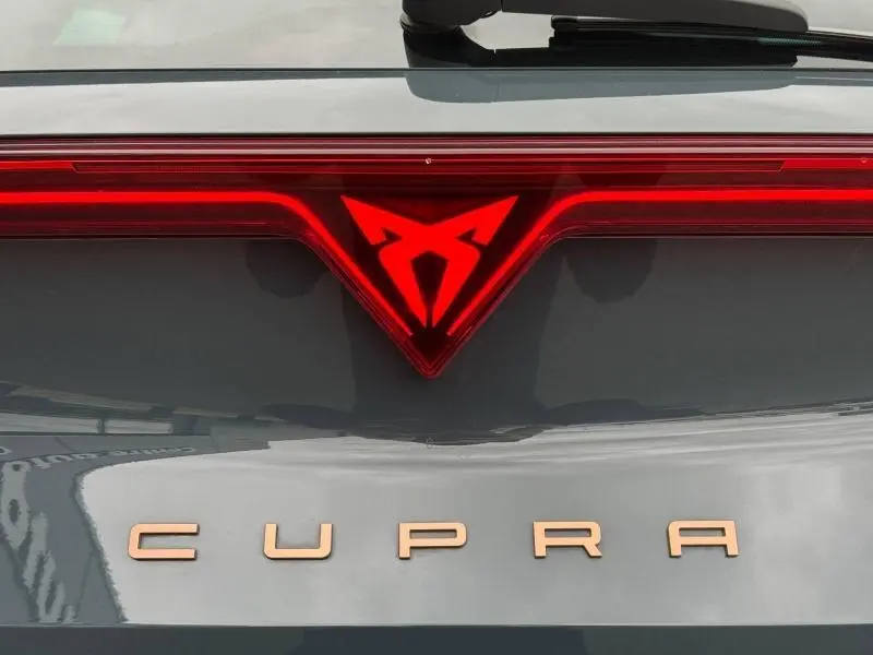 Gros plan sur le logo lumineux rouge et la signature CUPRA cuivrée à l'arrière d'un Formentor bleu Fjord 2025.