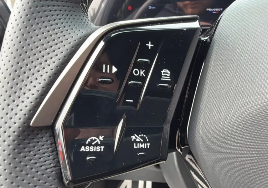 Gros plan sur les commandes multifonctions noires du volant cuir perforé du Peugeot 3008 Hybrid gris titane.