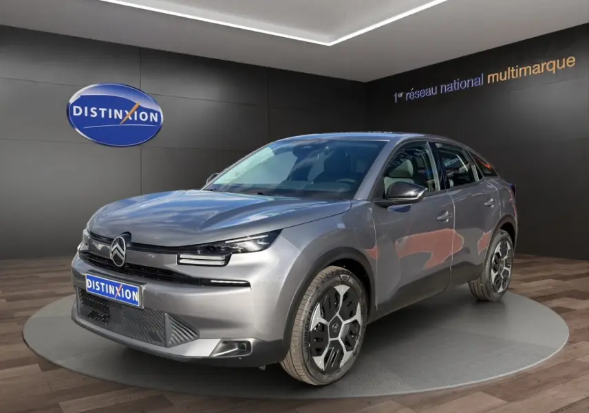 Citroën C4 hybride gris foncé vue 3/4 avant droit, avec phares LED et jantes distinctives en exposition showroom.