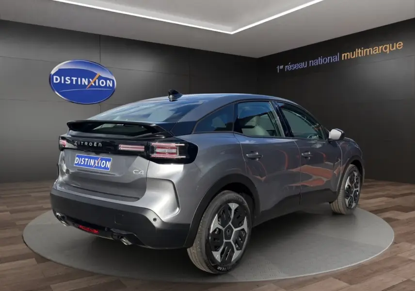 Vue 3/4 arrière droite d'une Citroën C4 hybride gris foncé avec jantes distinctives et toit noir brillant.