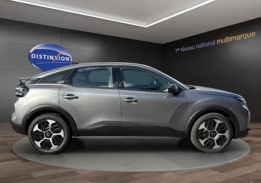 Profil droit d'une Citroën C4 hybride gris foncé avec jantes au design moderne, exposée en showroom.