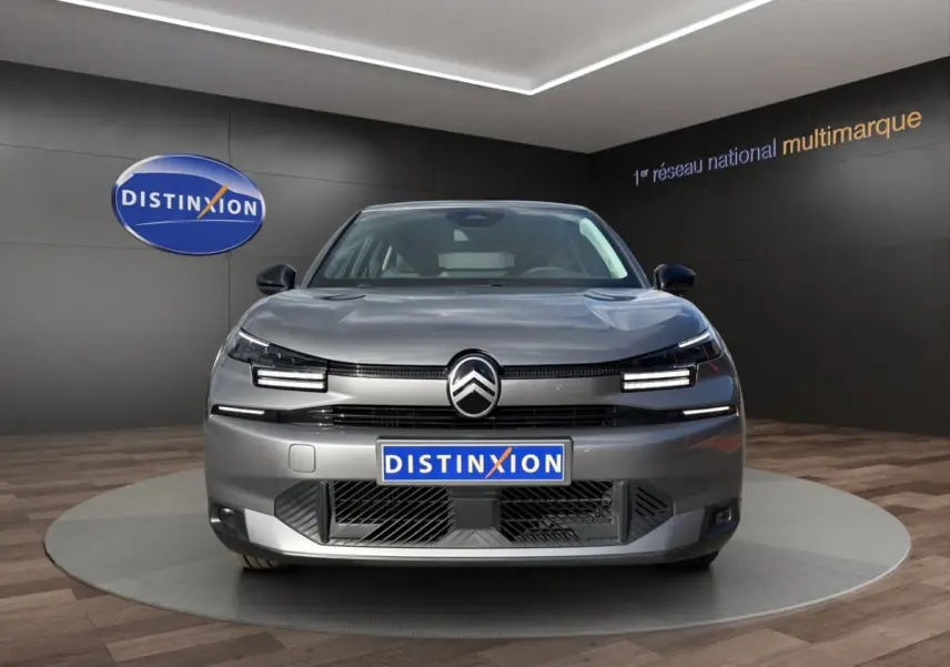 Vue frontale d'une Citroën C4 hybride gris foncé avec phares LED et calandre moderne en showroom.