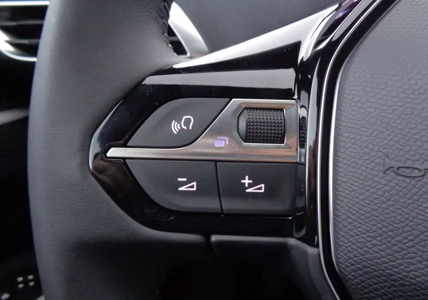 Gros plan sur les commandes vocales et volume du volant noir du Peugeot 5008 2023 finition Active Pack.