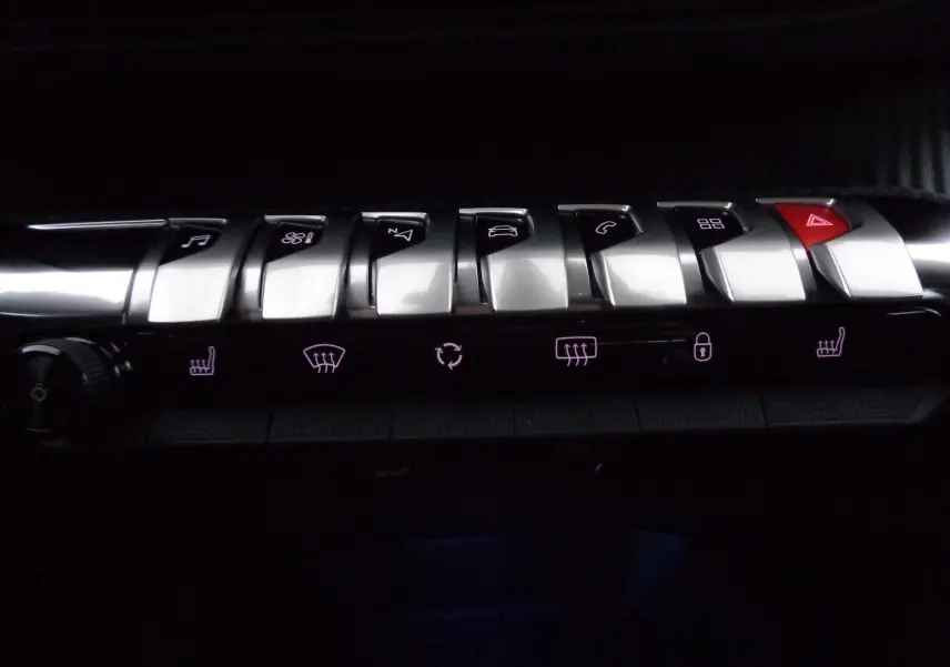 Gros plan sur la rangée de boutons chromés et lumineux du tableau de bord du Peugeot 5008 noir perle métal 2023.