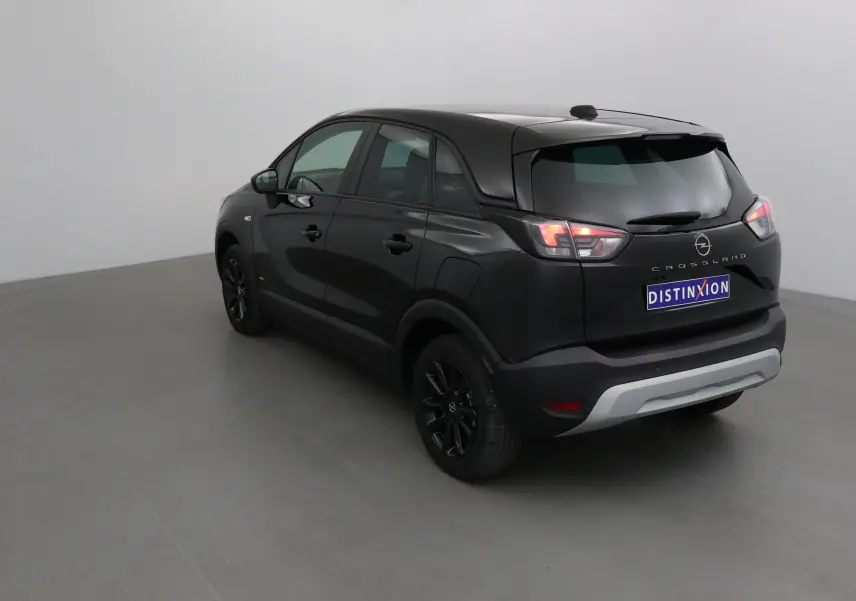 Opel Crossland noir vue 3/4 arrière droit, avec jantes noires et feux arrière allumés dans un studio.