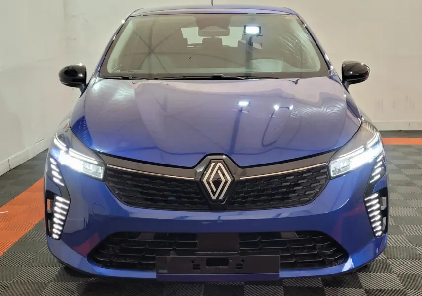 Vue frontale d'une Renault Clio Evolution Blue dCi 100 2025 en bleu avec phares LED allumés et calandre noire distinctive.