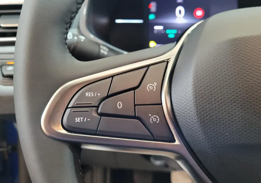 Gros plan sur les commandes du régulateur de vitesse à gauche du volant cuir de la Renault Clio bleu 2025.