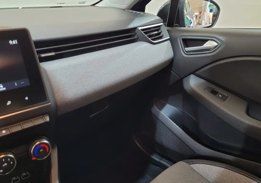Intérieur côté passager de la Renault Clio bleu 2025 montrant tableau de bord gris clair et portière noire.