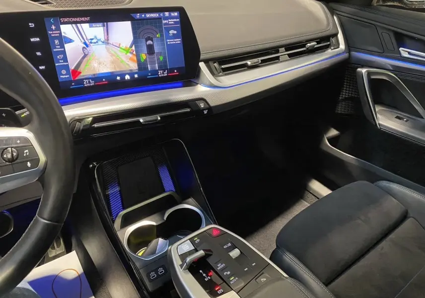 Intérieur BMW X1 XDRIVE 20D M SPORT 2025, vue console centrale avec écran tactile et éclairage d'ambiance bleu.