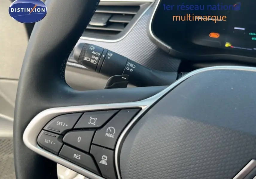 Gros plan sur les commandes au volant à gauche du Renault Arkana gris satin métal, avec tableau de bord numérique en arrière-plan.