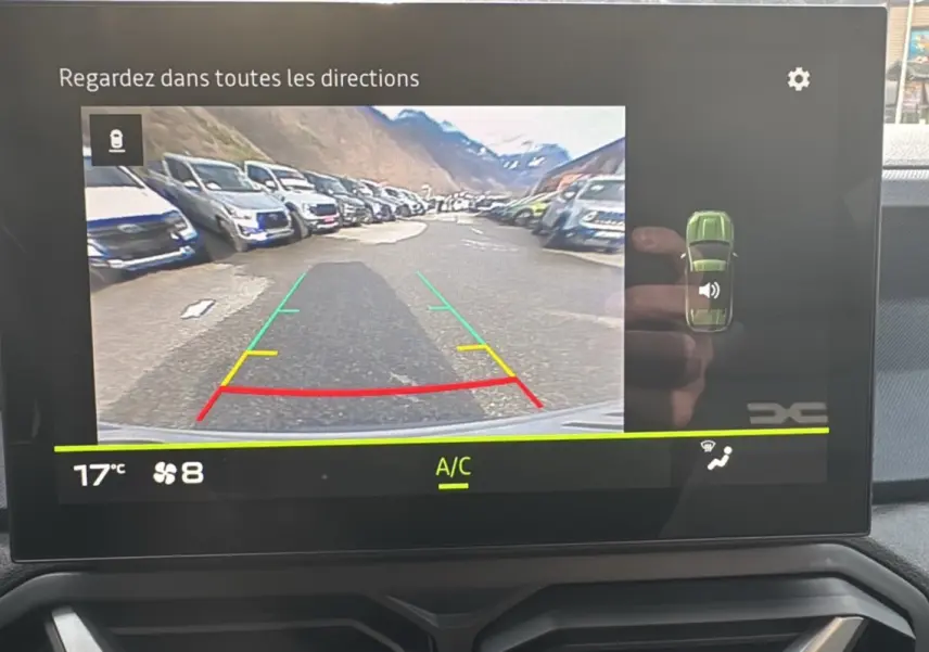 Écran multimédia du Dacia Duster 2025 montrant la caméra de recul avec guidage coloré et vue arrière du véhicule.