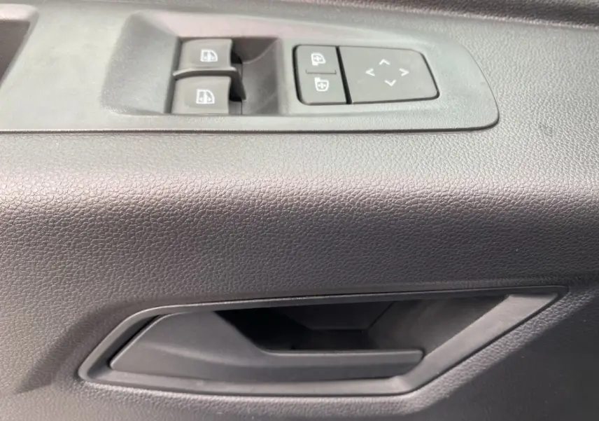 Poignée de porte intérieure côté conducteur avec commandes électriques des vitres et réglage des rétroviseurs du Renault Master blanc.