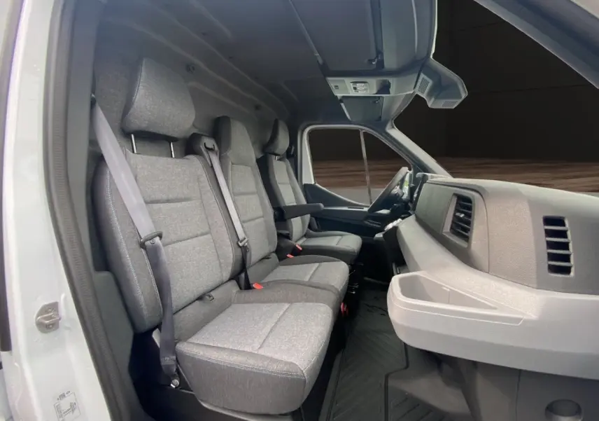 Vue intérieure côté gauche du Renault Master blanc 2026, montrant les sièges avant en tissu gris et le tableau de bord.