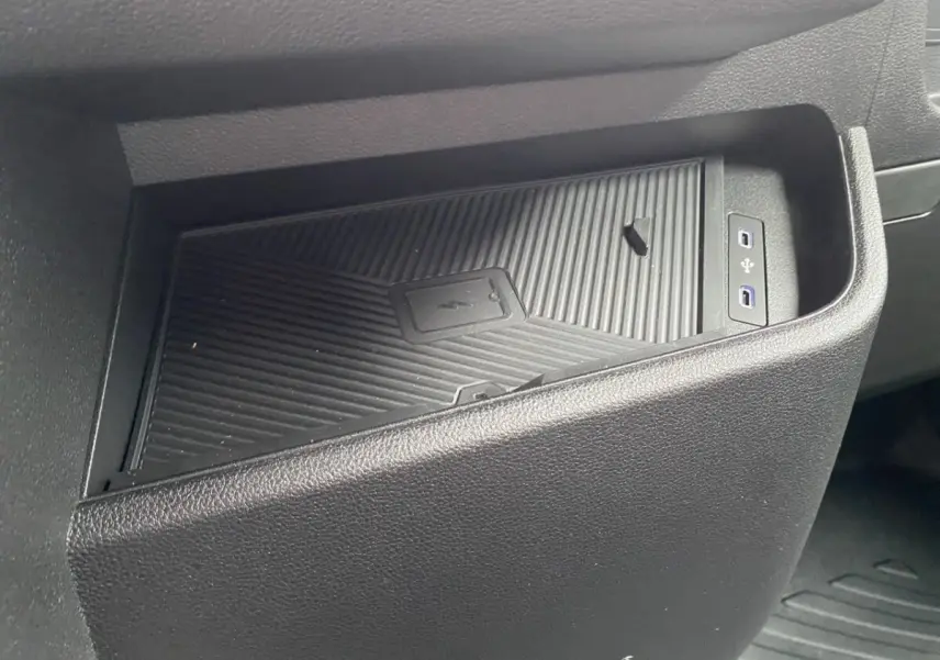 Gros plan sur le rangement central noir avec zone de recharge par induction et ports USB dans Renault Master blanc.