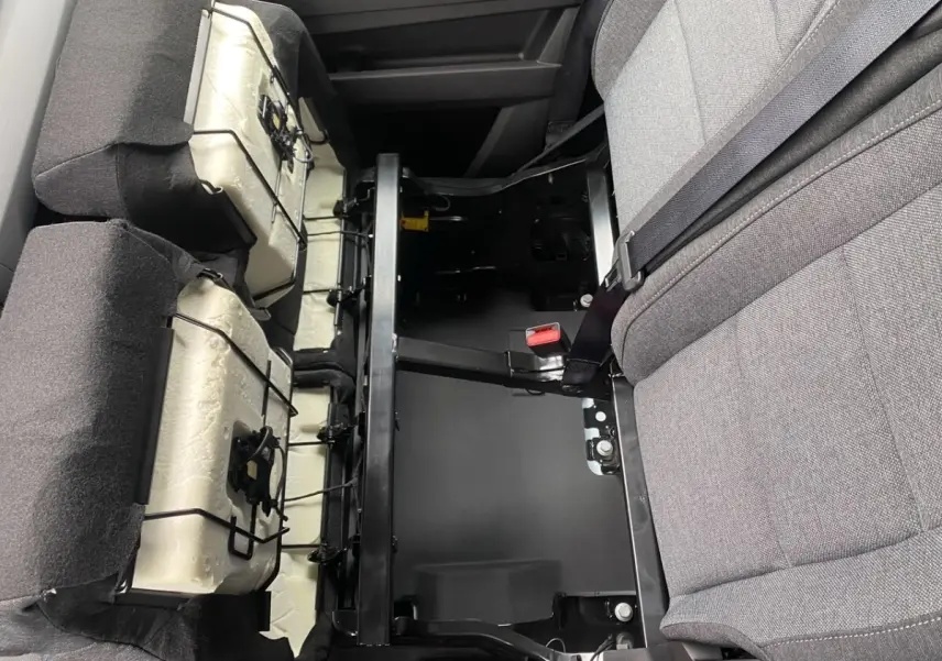 Vue rapprochée de l'intérieur arrière du Renault Master blanc, montrant la structure métallique et les sièges gris partiellement relevés.