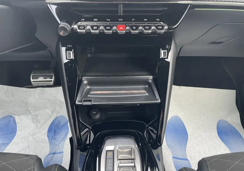Vue rapprochée de la console centrale noire brillante de la Peugeot 2008 1.2 PureTech, avec commandes tactiles et boîte auto.