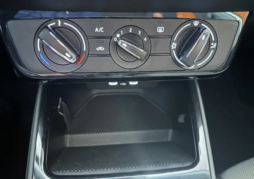 Gros plan sur les commandes de climatisation manuelle et la zone de rangement inférieure du tableau de bord de la Skoda Fabia Ambition gris argent 2023.