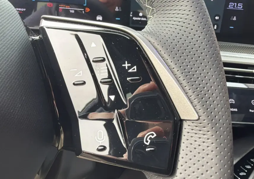 Gros plan sur le volant cuir perforé du Peugeot 3008 Hybrid 145 GT avec commandes multifonctions noires brillantes.