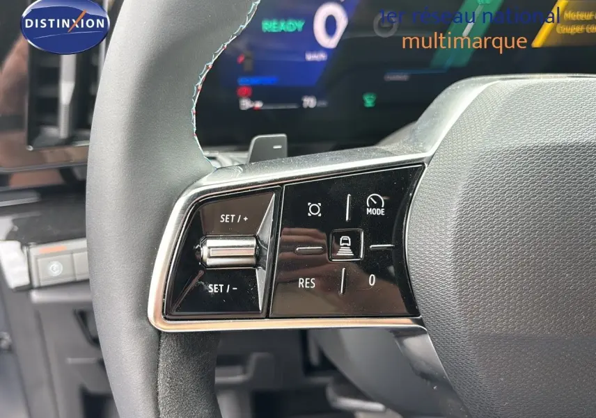 Gros plan sur les commandes du volant à gauche du Renault Austral gris schiste satin mat 2024, affichage numérique en arrière-plan.