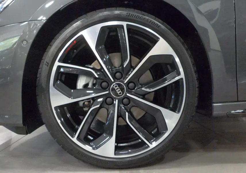 Gros plan sur la jante bi-ton noire et argentée de l'Audi A3 Sportback gris Daytona, version S-Line 2025.