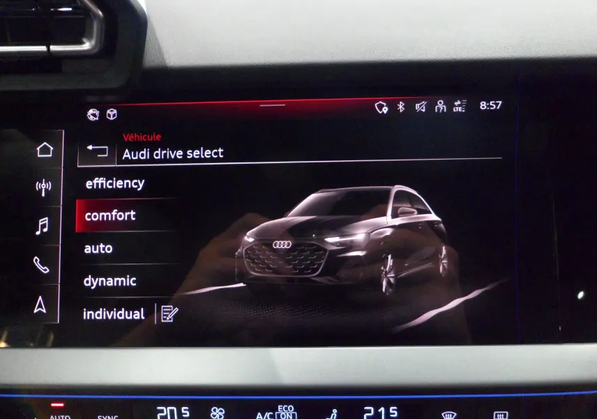Écran tactile intérieur montrant la sélection Audi Drive Select avec une illustration 3D d'une Audi A3 Sportback gris Daytona en vue 3/4 avant.