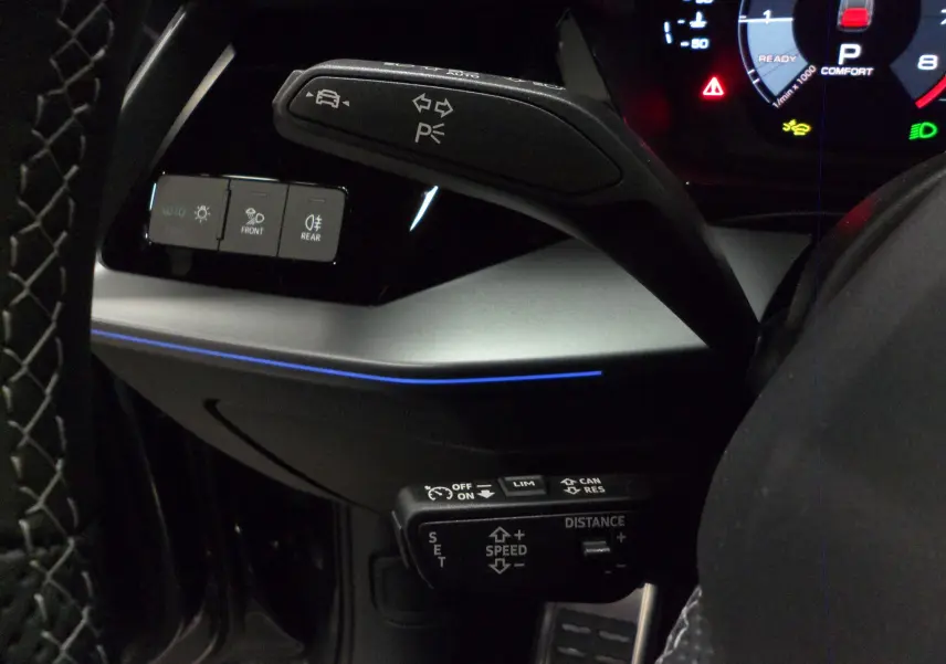 Détail du volant et commandes du régulateur adaptatif sur Audi A3 Sportback 2025 avec éclairage d'ambiance bleu