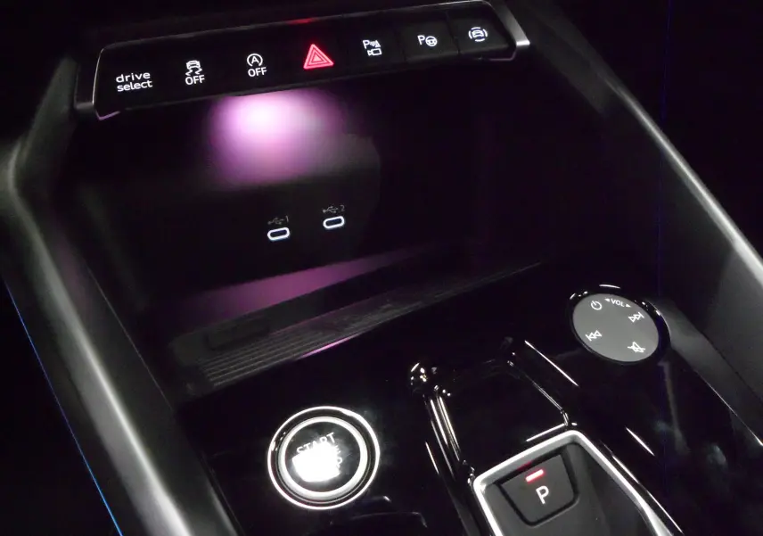 Gros plan sur la console centrale noire de l'Audi A3 Sportback 2025, avec bouton start/stop et commandes tactiles éclairées.