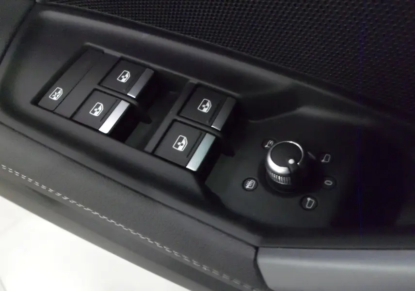 Gros plan sur les commandes des vitres et rétroviseurs côté conducteur de l'Audi A3 Sportback gris Daytona 2025.