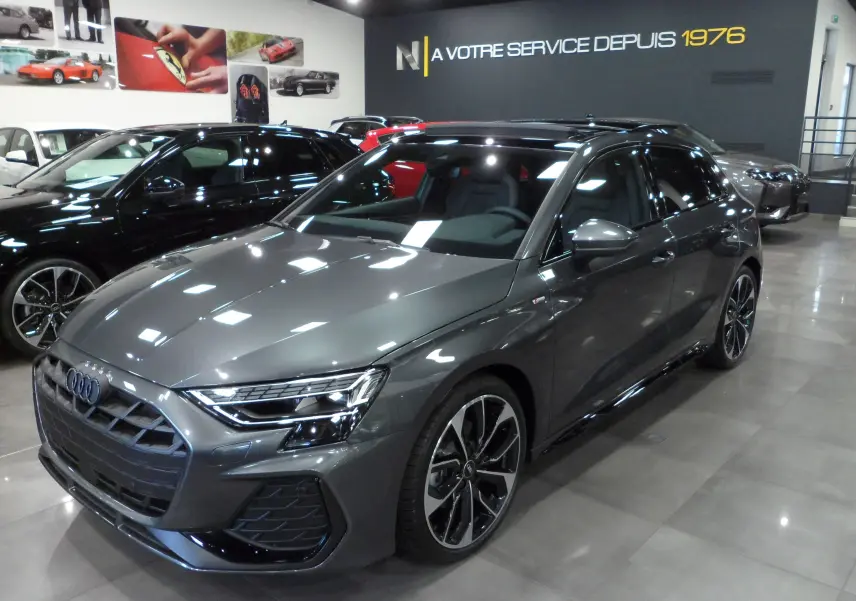 Audi A3 Sportback 35 TFSI S-Line gris Daytona vue 3/4 avant droit en intérieur showroom avec jantes bi-ton.