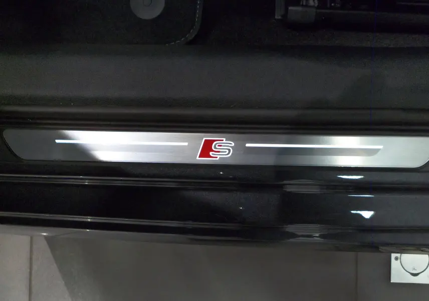 Gros plan sur la plaque de seuil de porte avec logo S rouge, intérieur noir de l'Audi A3 Sportback 2025.