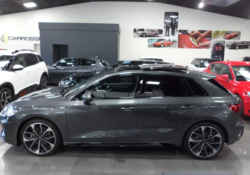 Profil côté gauche d'une Audi A3 Sportback 35 TFSI S-Line gris Daytona avec toit ouvrant en concession.