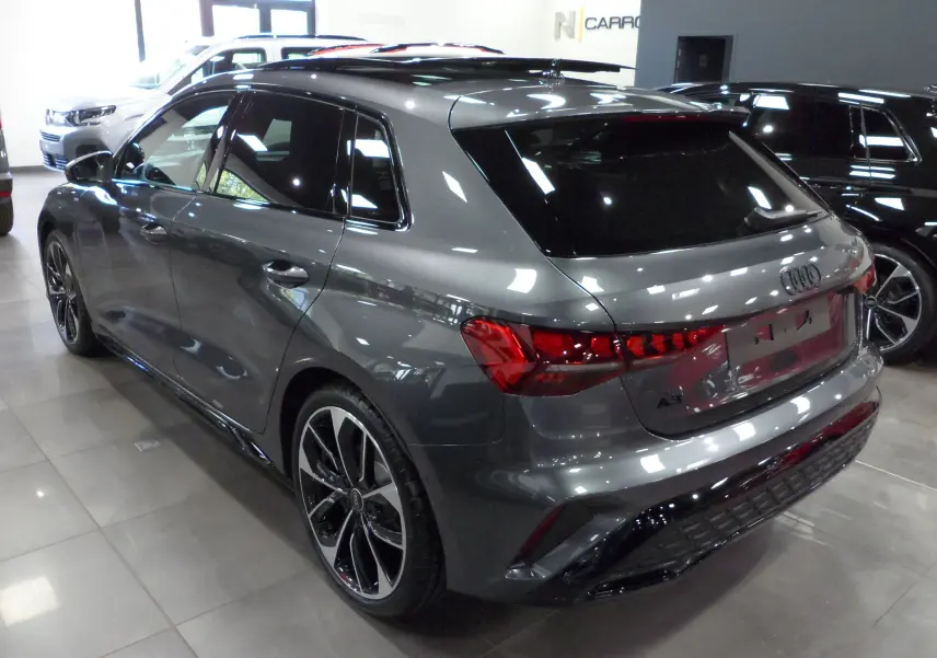 Audi A3 Sportback gris Daytona vue 3/4 arrière droit en showroom avec jantes noires bicolores distinctives