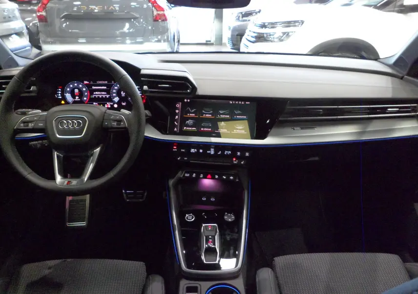 Intérieur Audi A3 Sportback 2025 vu de face, tableau de bord moderne avec éclairage d'ambiance bleu et écran tactile central.