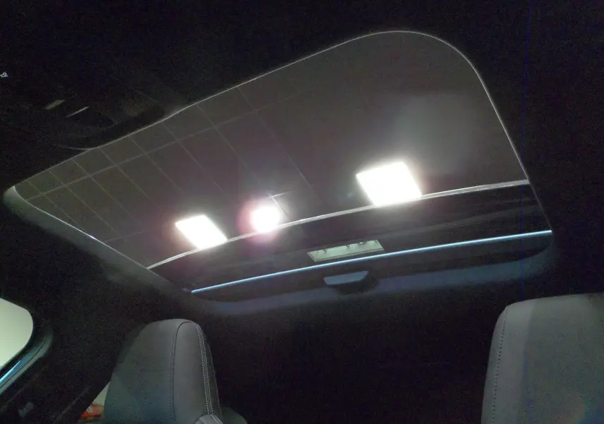 Toit panoramique ouvert vu de l'intérieur arrière de l'Audi A3 Sportback 35 TFSI gris Daytona avec sièges en cuir noir.