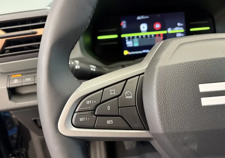 Gros plan sur le volant cuir synthétique côté gauche du tableau de bord du Dacia Duster noir 2025 avec commandes multifonctions.