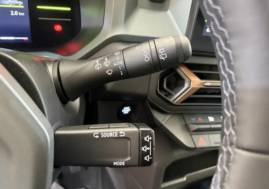 Gros plan sur les commandes au volant du Dacia Duster noir 2025, montrant les leviers de clignotants et multimédia.