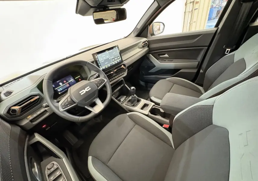 Intérieur du Dacia Duster 2025 vue côté conducteur, tableau de bord moderne avec écran tactile et volant multifonctions.