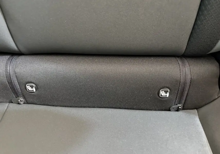 Détail des attaches Isofix sur la banquette arrière noire du Dacia Duster 2025 hybride essence.