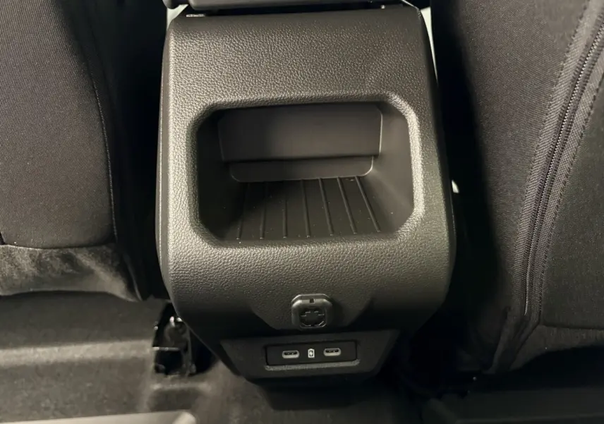 Prise USB arrière et rangement noir entre les sièges arrière du Dacia Duster 2025 hybride essence.